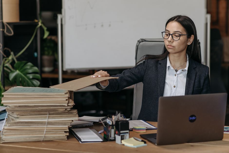 산더미처럼 쌓인 종이 서류와 서류 파쇄기
